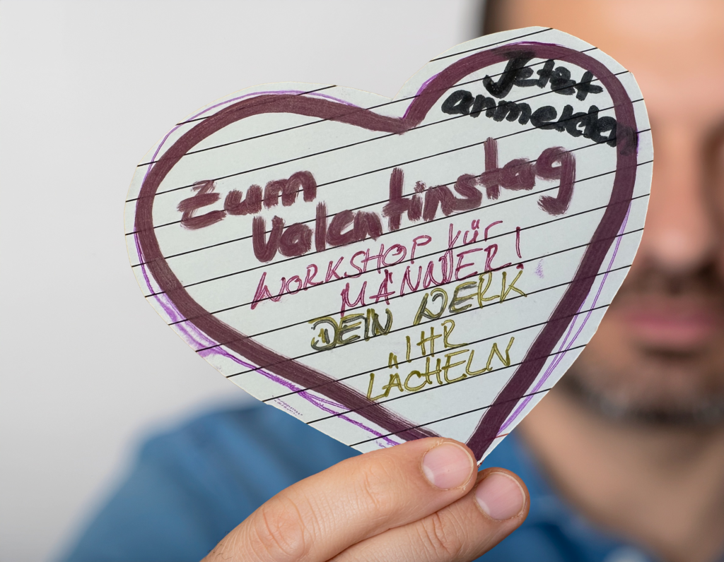 Fotorealistisches Titelbild zum Valentins-Kurs: Ein Mann hält ein handgemachtes Herz im Fokus der Kamera – persönlich, emotional und kreativ. Ein selbstgestaltetes Geschenk von Herzen.